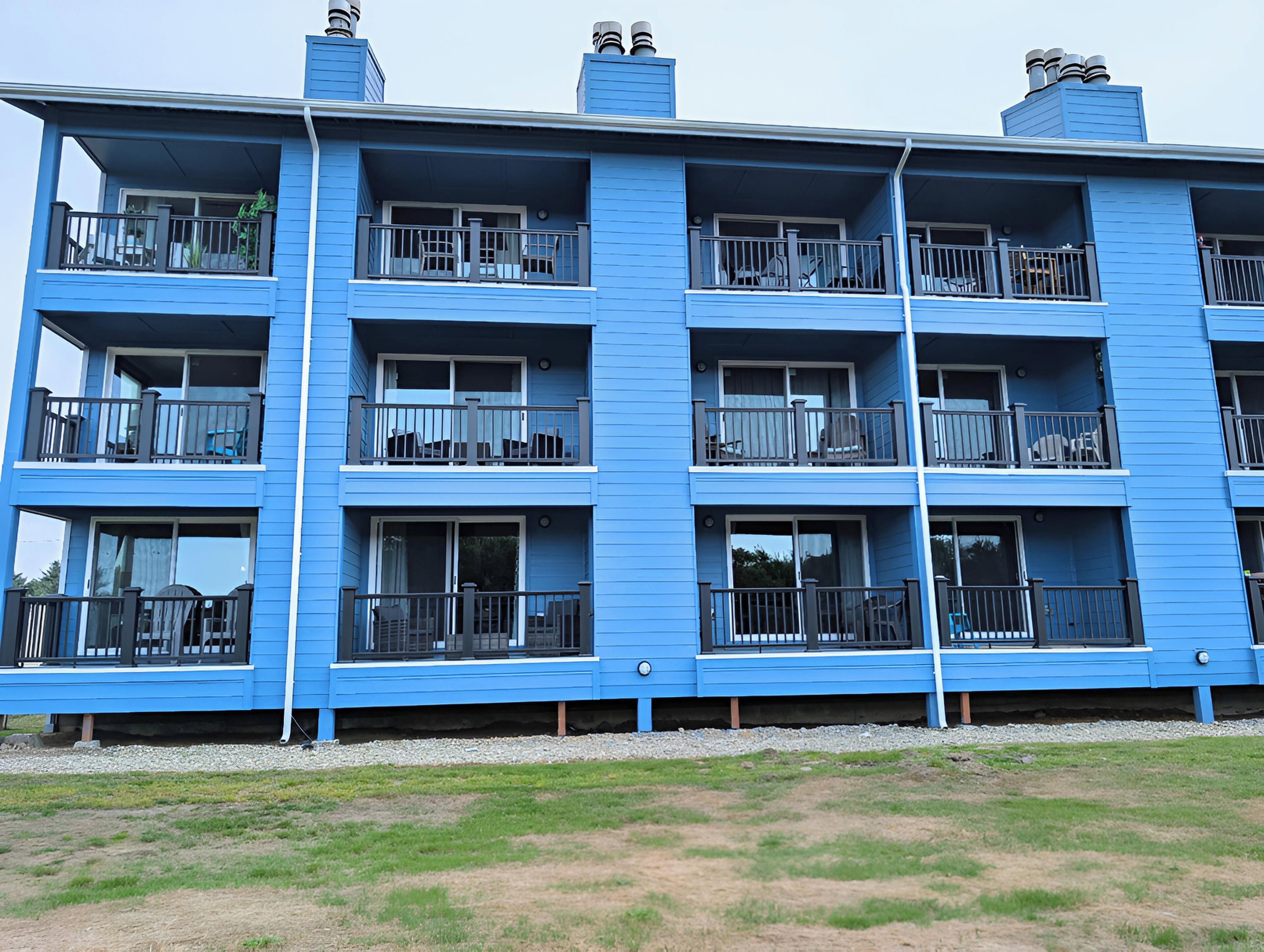 Un immeuble bleu à plusieurs étages, doté de balcons, de fenêtres et de cheminées.