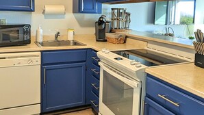 A kitchen with blue cabinets, a white stove, a microwave, and a sink. - Calypso at Nautilus (Ocean Shores)