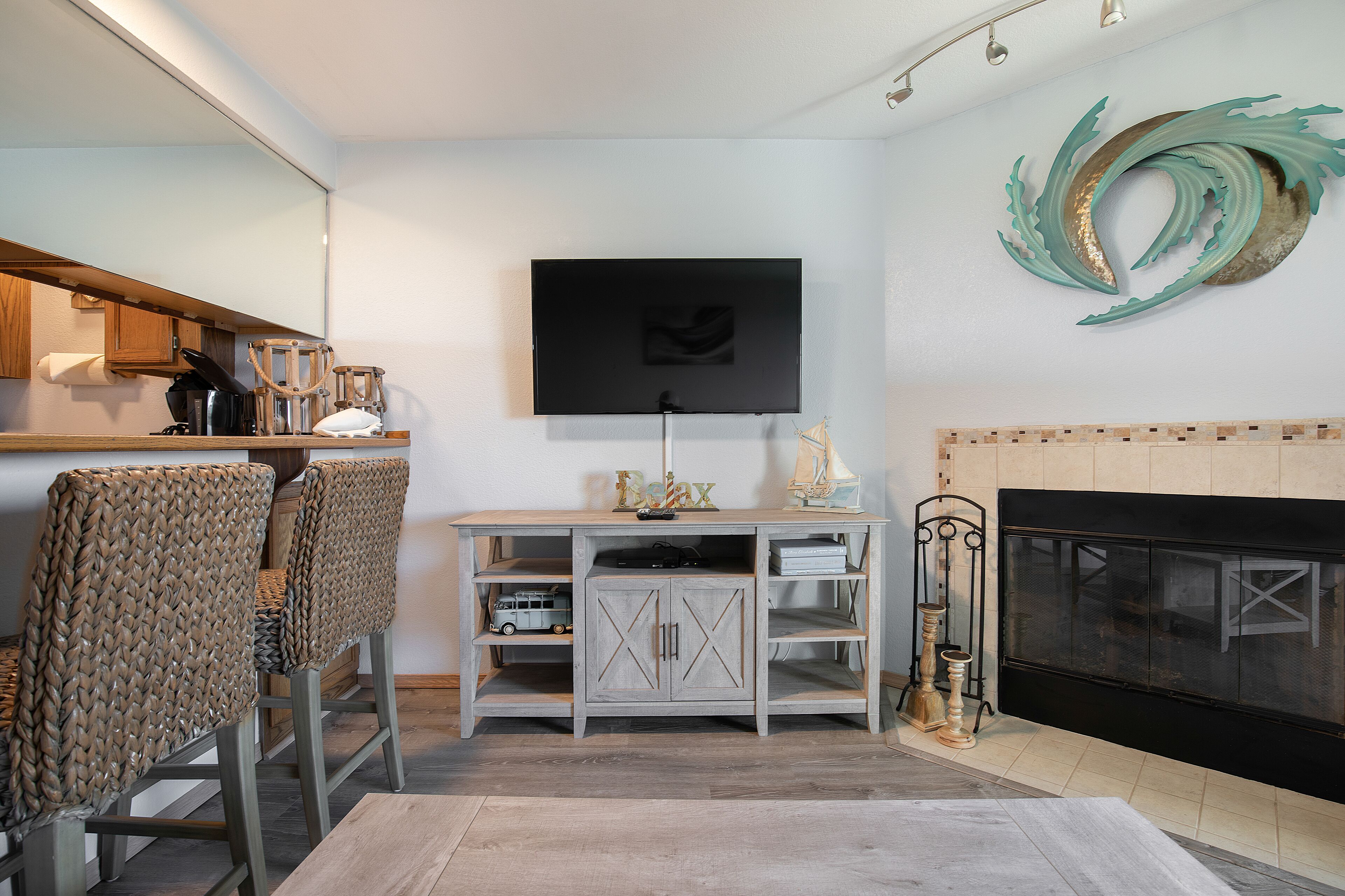 Una sala de estar con televisor, chimenea y sillones de mimbre.