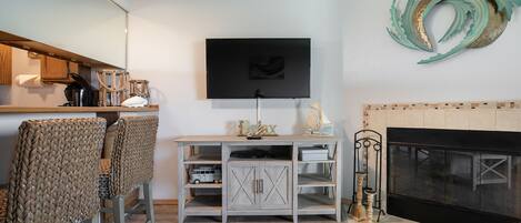Una sala de estar con televisor, chimenea y sillones de mimbre.