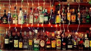 Un bar avec différentes bouteilles d’alcool et un mur en briques en arrière-plan.