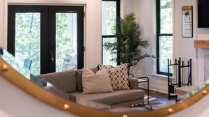 Una sala de estar con sofá, una silla colgante, una planta grande en maceta y una chimenea.