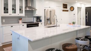 Una cocina moderna con armarios blancos, electrodomésticos de acero inoxidable y encimera de mármol.