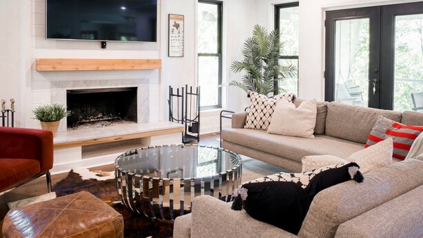 Una sala de estar moderna con chimenea, un televisor de pantalla plana grande, un sofá cómodo y una mesa de centro de vidrio.