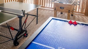 Een kamer met een tafeltennistafel, een tafelvoetbaltafel en een pooltafel.
