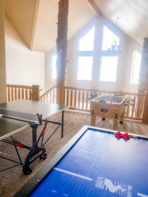 Una habitación con mesa de ping pong, mesa de fútbol de mesa y mesa de billar.