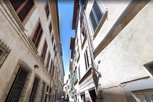 Una calle estrecha flanqueada por edificios, con numerosas ventanas y balcones.