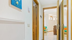 Un pasillo con una puerta de madera que da a una habitación con un sofá colorido y una mesita.