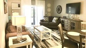 Ein Wohnzimmer mit Sofa, Couchtisch, Fernseher und einem Essbereich mit Tisch und Stühlen.
