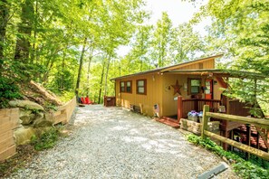 A cabin with a gravel driveway, wooden deck, and a star decoration on the front. - Mountain Views | Hot Tub | Family Cabin (Almond)
