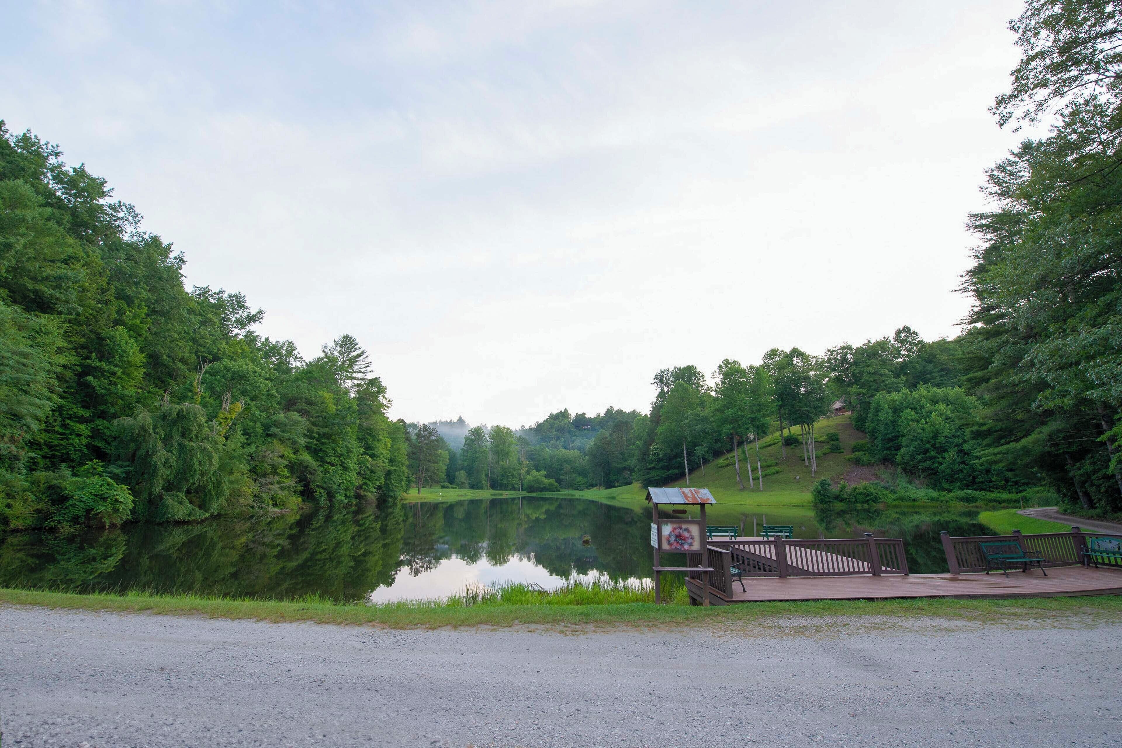 A tranquil lakeside park with a wooden deck, benches, and a gazebo.