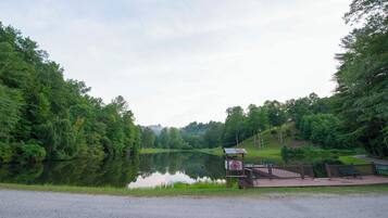 A tranquil lakeside park with a wooden deck, benches, and a gazebo.