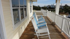 A wooden deck with white railings and blue rocking chairs.