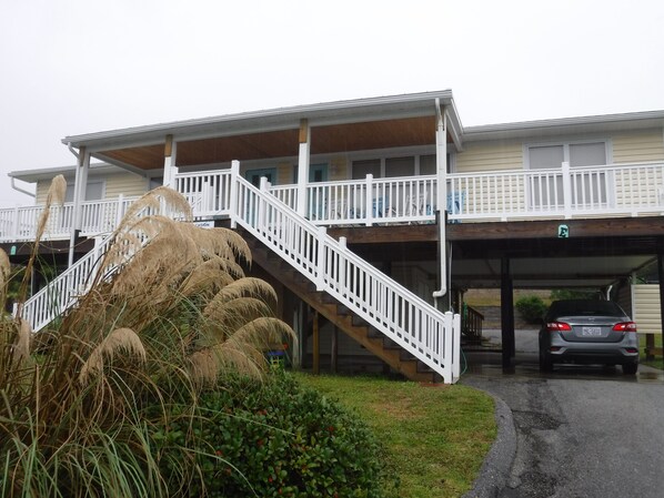 A two-story building with a covered outdoor area and a car parked in the garage.