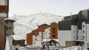 Ein schneebedeckter Berg mit Gebäuden im Vordergrund.