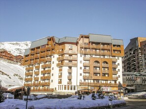 Un hôtel à plusieurs étages, doté de balcons en bois, avec des pistes de ski en arrière-plan.