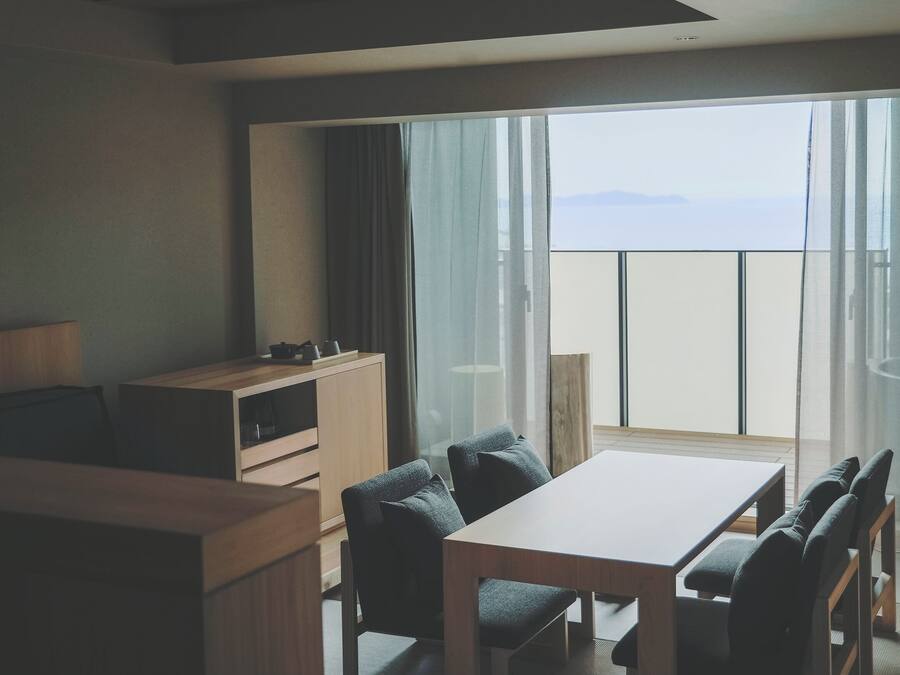 Habitación de hotel con balcón, un escritorio de madera, una silla, un sofá y un televisor.