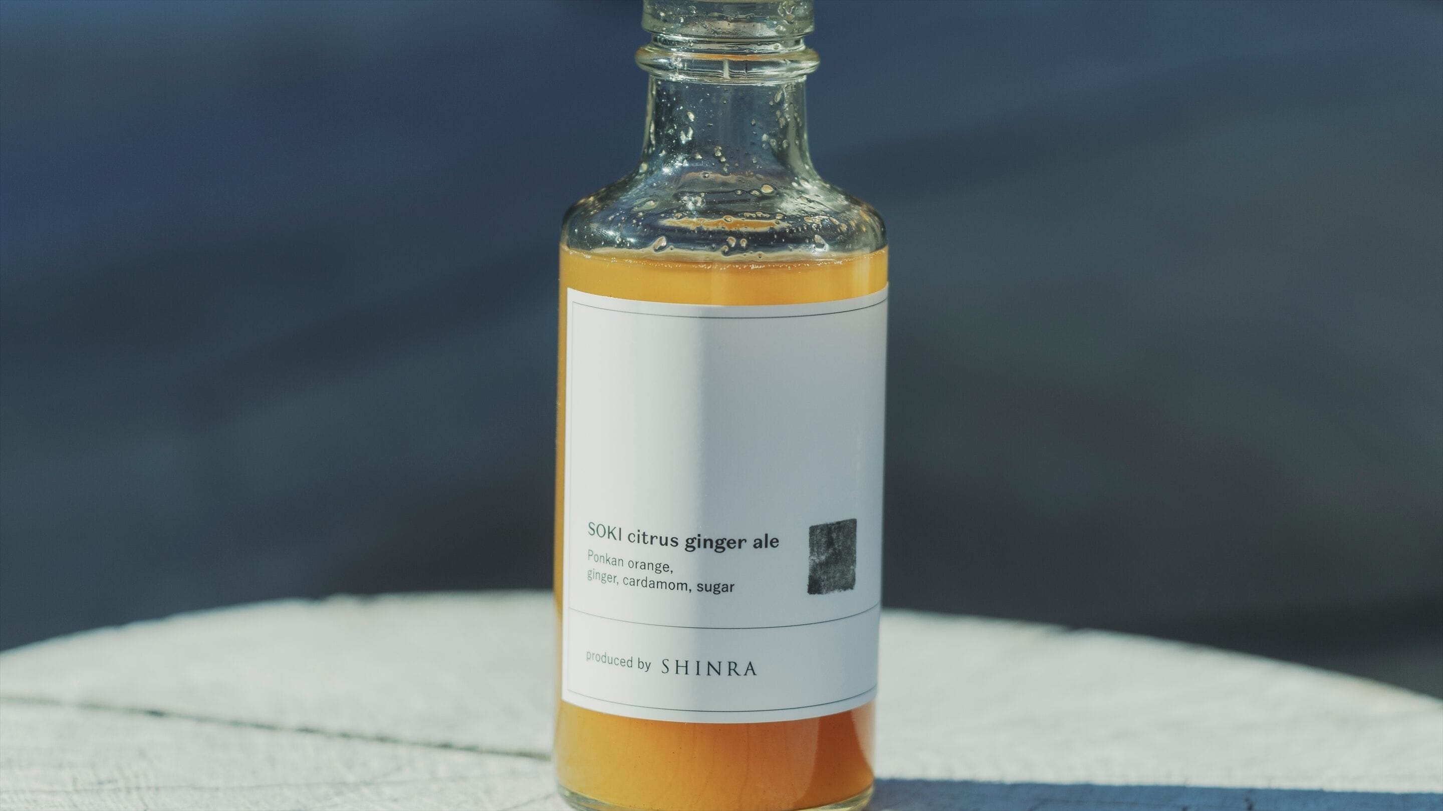 Une bouteille de SOKI, une boisson gazeuse aux agrumes et au gingembre, dont l’étiquette indique les ingrédients suivants : orange ponkan, gingembre, cardamome et sucre. Produit par SHINRA.