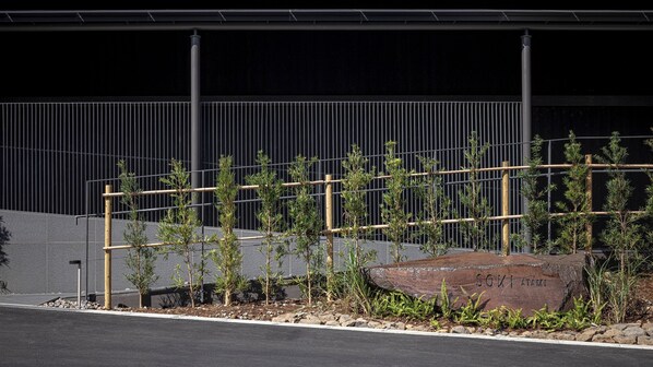 A landscaped area with young trees, a large rock with 'SOKIMAMI' engraved, and a metal fence. - SOKI ATAMI (Atami)