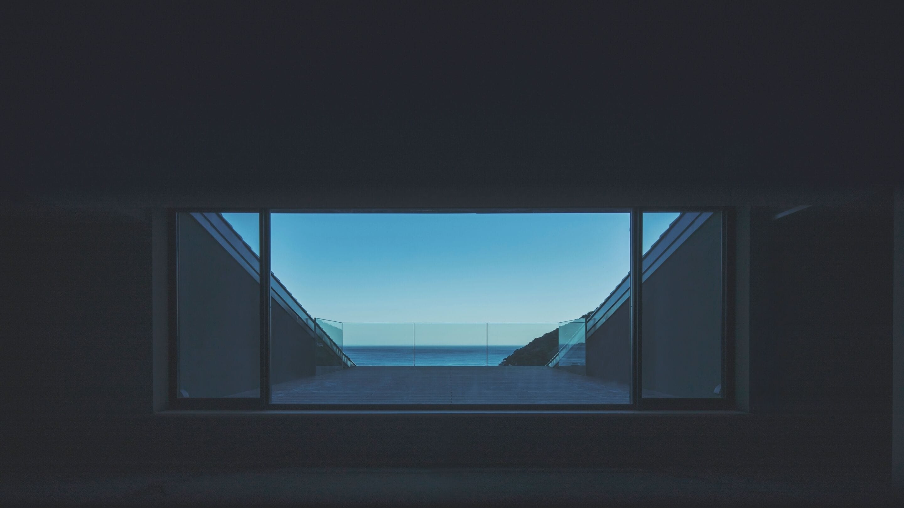 Una habitación con un gran ventanal que ofrece vistas al mar y una escalera que lleva a un espacio exterior.
