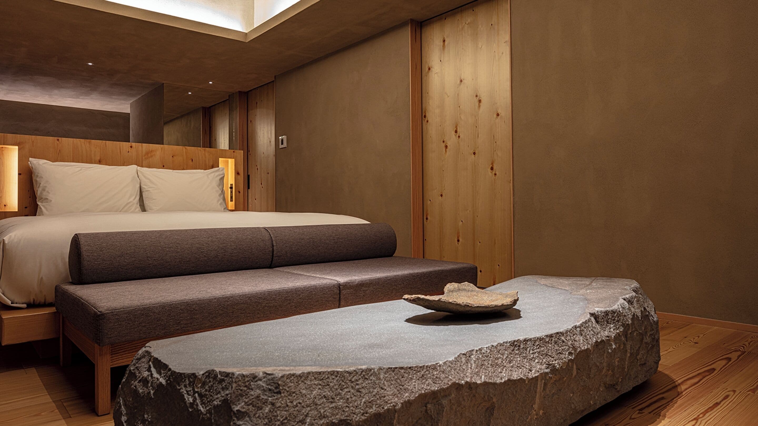 Ein modernes Schlafzimmer mit einem Bett, einer Bank und einem Steintisch.