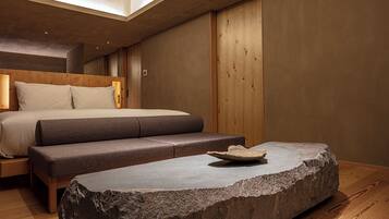 Ein modernes Schlafzimmer mit einem Bett, einer Bank und einem Steintisch.