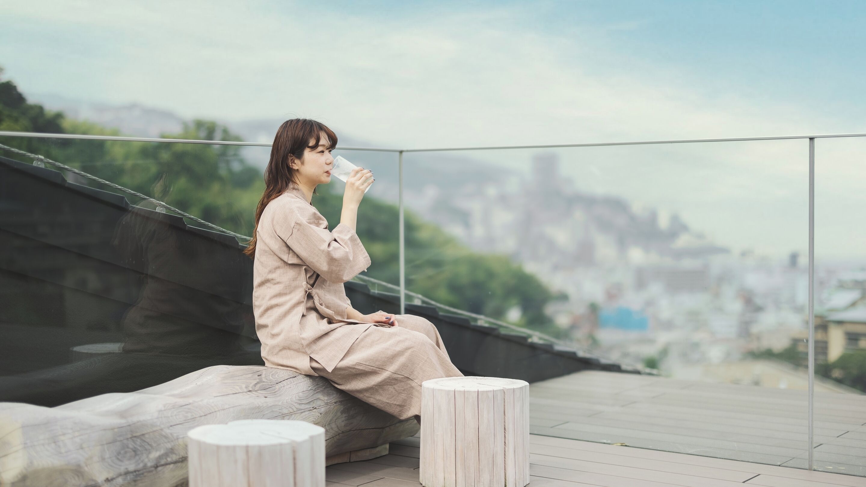 A person sitting on a wooden bench with a cityscape view in the background.