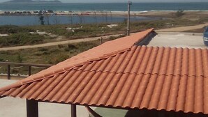 Ein Gebäude mit rotem Ziegeldach, einem Balkon mit Geländer und Blick auf das Meer und das entfernte Land.