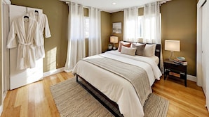 A bedroom with a bed, bedside tables, a nightstand, a mirror, and a wardrobe. - Hidden Gem Villa | Heated Pool, Hot Tub & Tikihut (Fort Lauderdale)