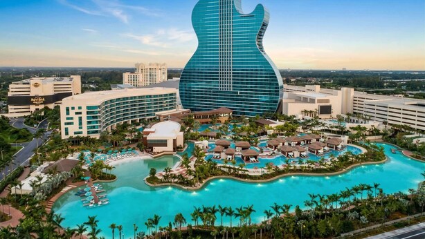 A hotel with a guitar-shaped building, a large pool, and multiple guest rooms. - Hidden Gem Villa | Heated Pool, Hot Tub & Tikihut (Fort Lauderdale)