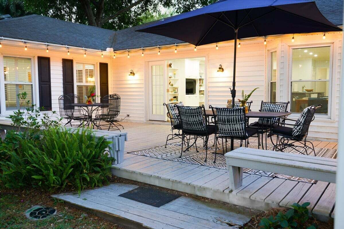 An outdoor patio with a table and chairs, surrounded by a wooden deck and a large umbrella.
