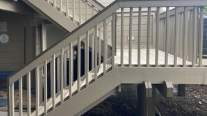 A wooden staircase with a handrail leading to a landing.
