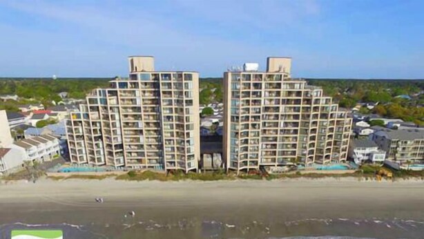 Ein Strandhotel mit mehreren Hochhäusern, einem Sandstrand und freiem Blick auf den Ozean.