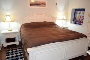 Un letto rifatto con cura, una coperta marrone, un poggiatesta bianco e due comodini con lampade.