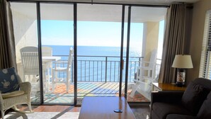 Ein Zimmer mit Meerblick, ein Balkon mit Stühlen, einem Tisch und einer Couch.