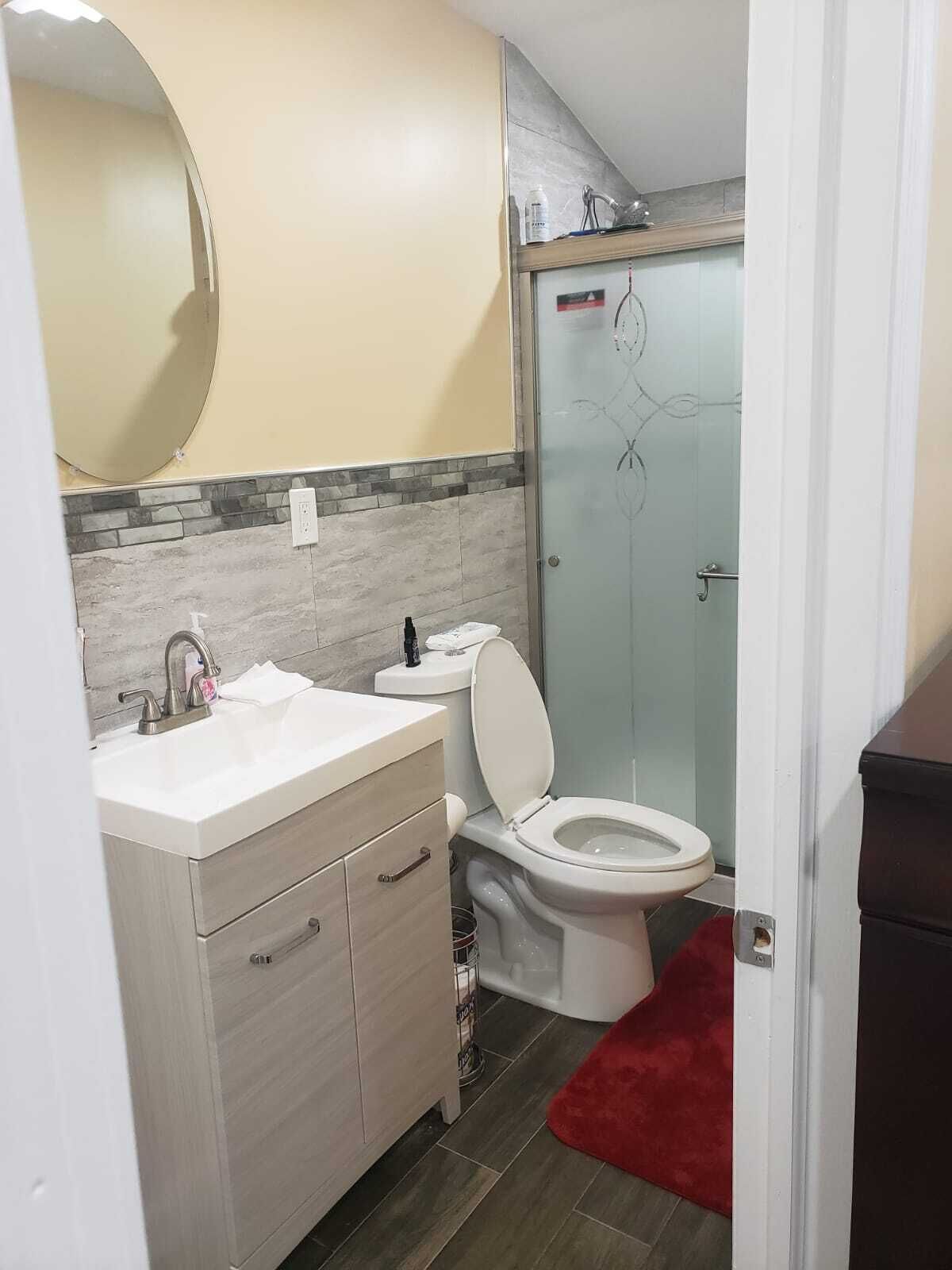 Un baño pequeño con un lavabo blanco, un inodoro y una cabina de ducha con mampara de vidrio.