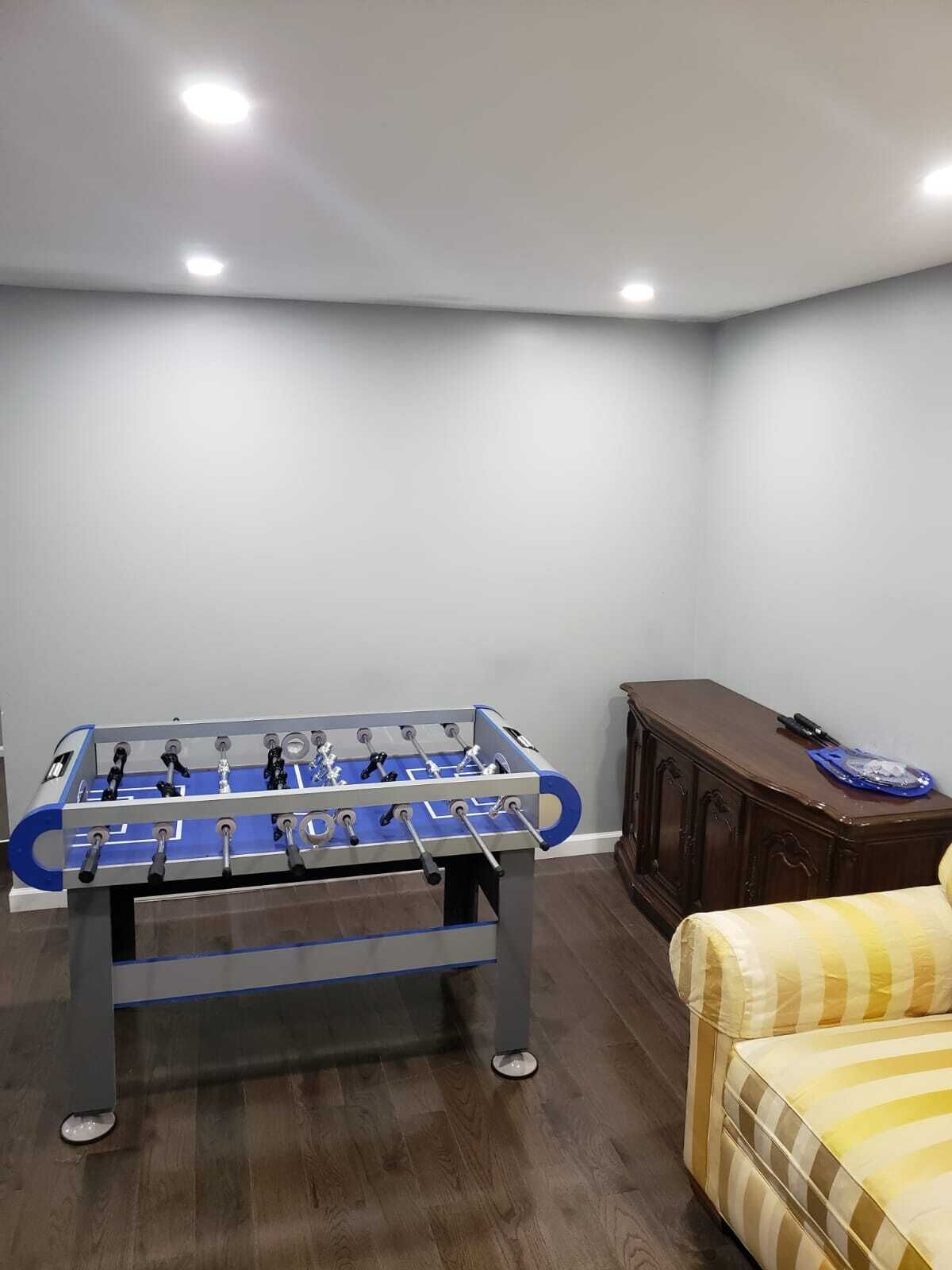 Una habitación con mesa de fútbol, un mueble de madera y un sofá a rayas.