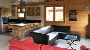 Una cocina moderna con una isla central, un sofá de cuero negro y un sofá rojo.