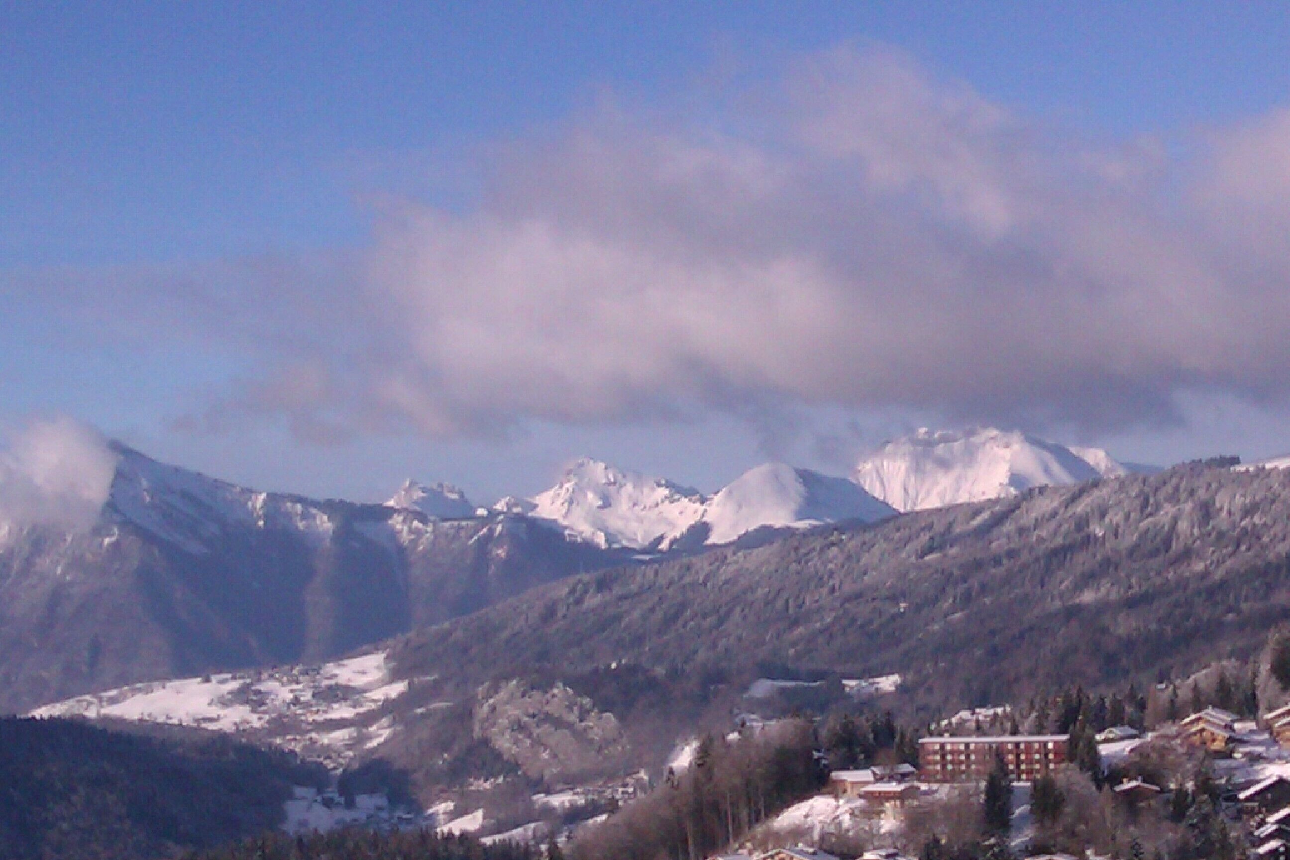 Paisaje montañoso con picos nevados y un edificio con múltiples ventanas en primer plano.