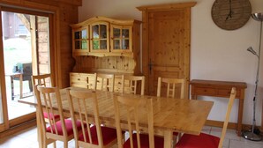 Un comedor de madera con una mesa grande y sillas, un aparador y un reloj en la pared.