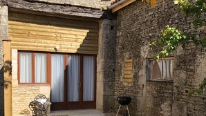 A stone building with a wooden door, a small patio with a table and chairs, and a barbecue grill. - BlanzayAprtment/1bed/Pool/Bbq/Wifi/FreeP (Blanzay)