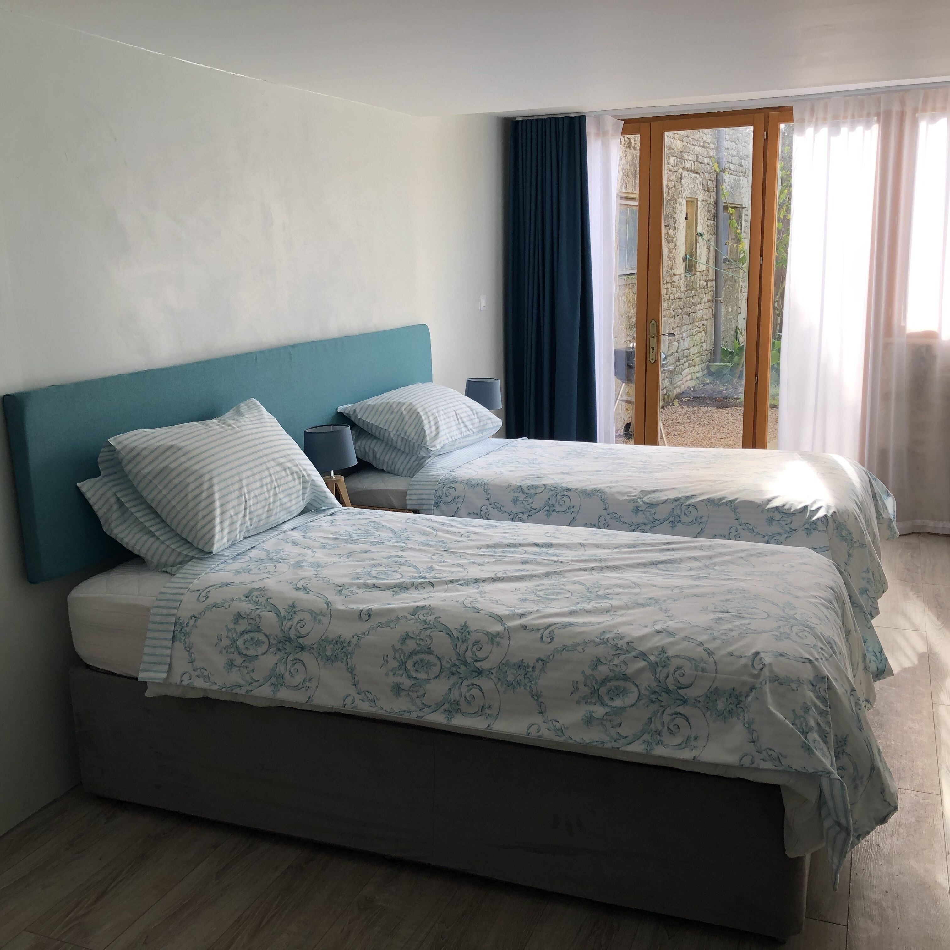 A double bed with a teal headboard, two bedside tables, and a patterned bedspread.
