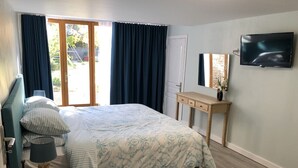 A bedroom with a bed, a bedside table, a lamp, a TV, and a sliding glass door to the outside. - BlanzayAprtment/1bed/Pool/Bbq/Wifi/FreeP (Blanzay)
