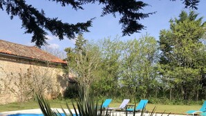 A swimming pool with lounge chairs, surrounded by greenery and a stone wall. - BlanzayAprtment/1bed/Pool/Bbq/Wifi/FreeP (Blanzay)