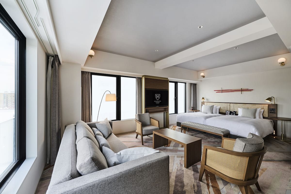 A modern hotel room with a large bed, a sofa, a chair, and a television.