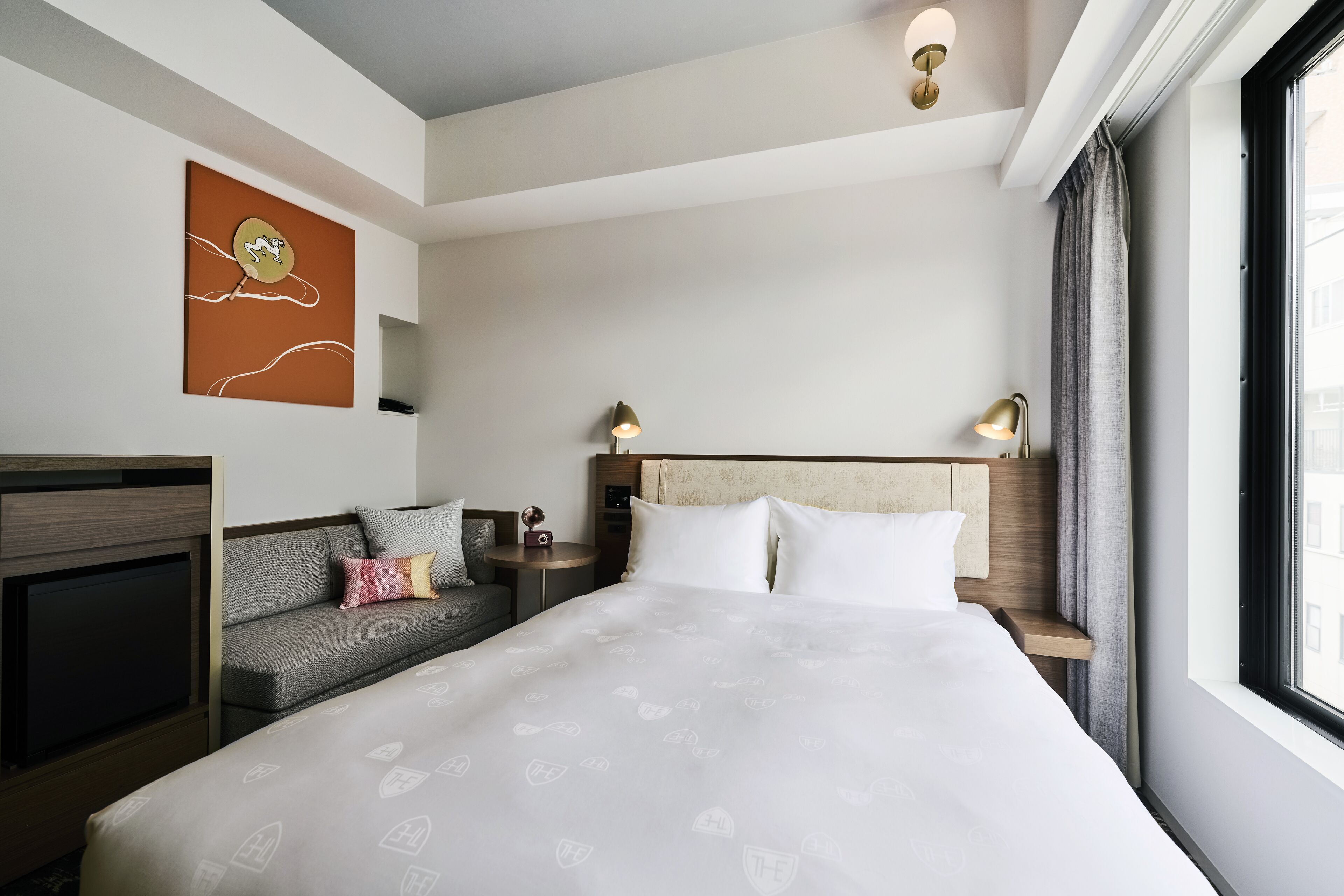 Une chambre d’hôtel avec un grand lit, un canapé, une télévision et une fenêtre avec des rideaux.