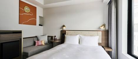 A hotel room with a large bed, a sofa, a TV, and a window with curtains.