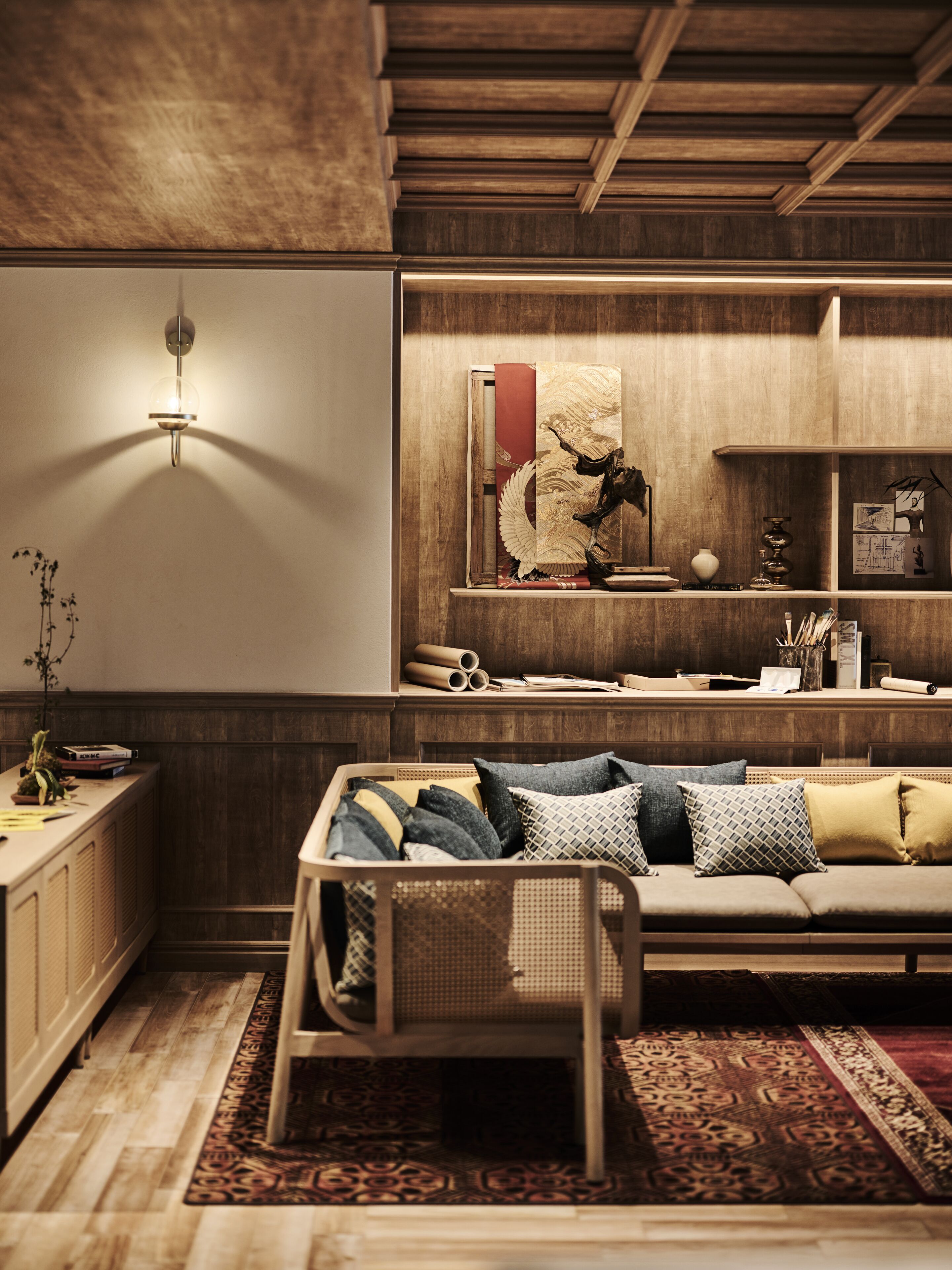 Una sala de estar acogedora con un sofá, almohadones decorativos, un mueble de madera y un estante montado en la pared con libros y un jarrón.