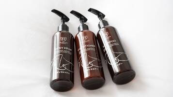 Three bottles of body wash and conditioner on a white surface.