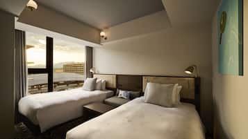 A hotel room with two beds, a small seating area, and a large window offering a city view.